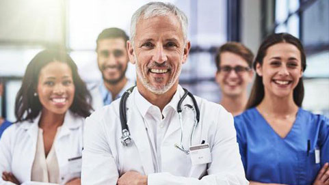 Doctors in white coats and scrubs smiling