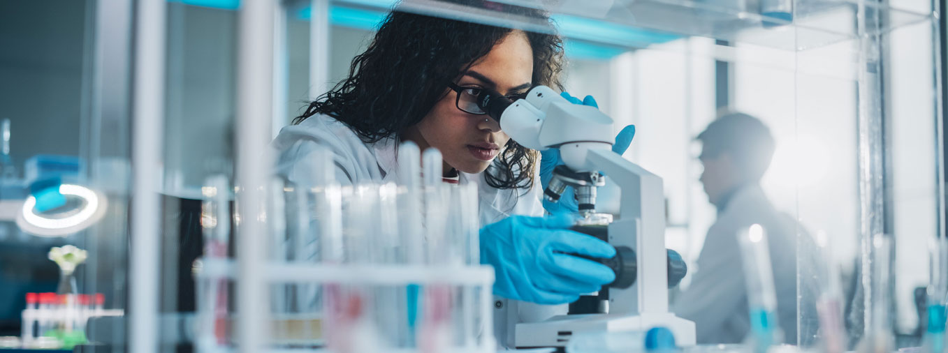 Female research scientist looking into a microscope. iStock photo. Credit: gorodenkoff